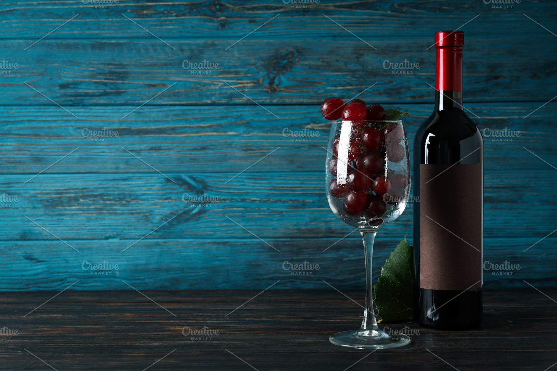 Bottle of wine, glass of grape and leaf on wooden table, a Food & Drink Photo by AtlasStudio PRO