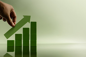 Hand placing green arrow on stacked bars, representing financial, a Photo by salmon.black