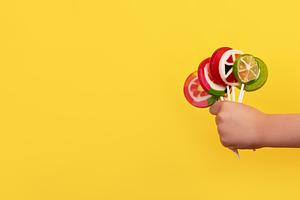 Kid's hand holding a bunch of vibrant fruit-shaped lollipops on, a Food & Drink Photo by Ales Munt