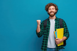 Happy student holding books celebrat, a Photo by Pixeness Studio