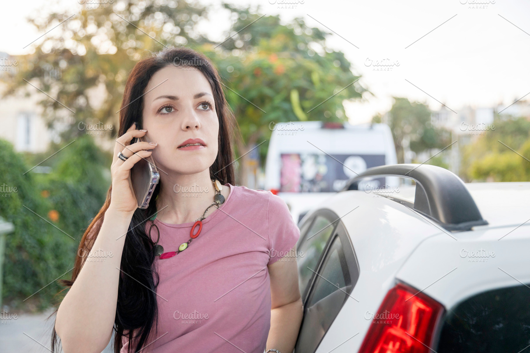Woman standing by a white car, looking focused while talking on, a Person Photo by Imaginarium