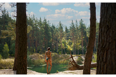 Woman in forest beside a serene lake