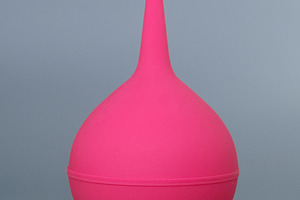 Pink rubber medical syringe bulb on a grey background. Disposable rubber enema, a Health & Medical Photo by Rohan Photography