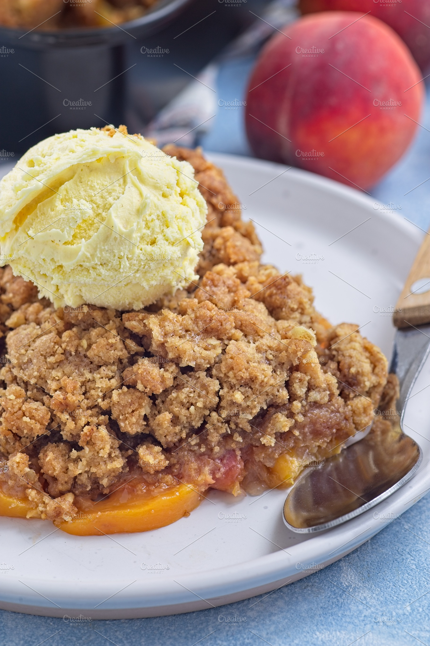 Delicious Peach Crisp or cobbler on plate with scoop of vanilla ice cream, vert, a Food & Drink Photo by iuliia_n
