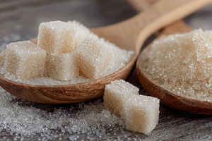 White sugar cubes and granulated sugar in wooden spoons, with br, a Photo by Studio ANNA