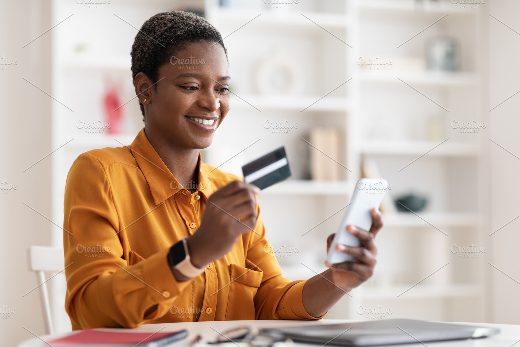 Happy african american woman using smartphone and credit card, a Photo by Prostock-Studio