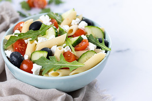 Mediterranean Pasta Salad in bowl with Fresh Vegetables and Herbs on green back, a Food & Drink Photo by etorres69
