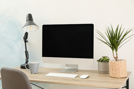 Workplace with computer, plants and lamp on wooden table. Empty, a Business Photo by AtlasStudio