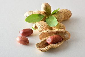Group of peeled and unpeeled peanuts with leaves on table, a Food & Drink Photo by Davizro's Market