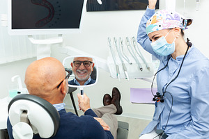 Happy senior man admiring his new smile in the mirror at the dentist, a Health & Medical Photo by Antonio Gravante Market