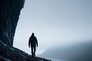 A lone person walking along a rocky, a Person Photo by MistyDay