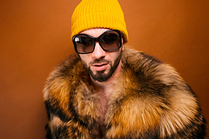 Man wearing fur coat, yellow beanie, and sunglasses, a Photo by karrastock