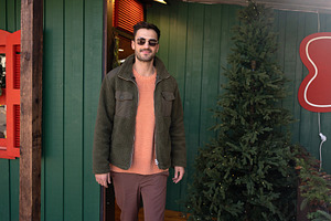 Handsome man in jacket standing outside green house during Christmas, a Person Photo by andreonegin market