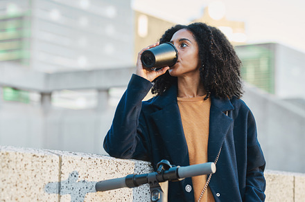 Drinking coffee, electric scooter and city with a business black woman on her morning commute into work. Tea, transport and carbon footprint with a female employee traveling in an urban town alone, a Photo by Peopleimages.com