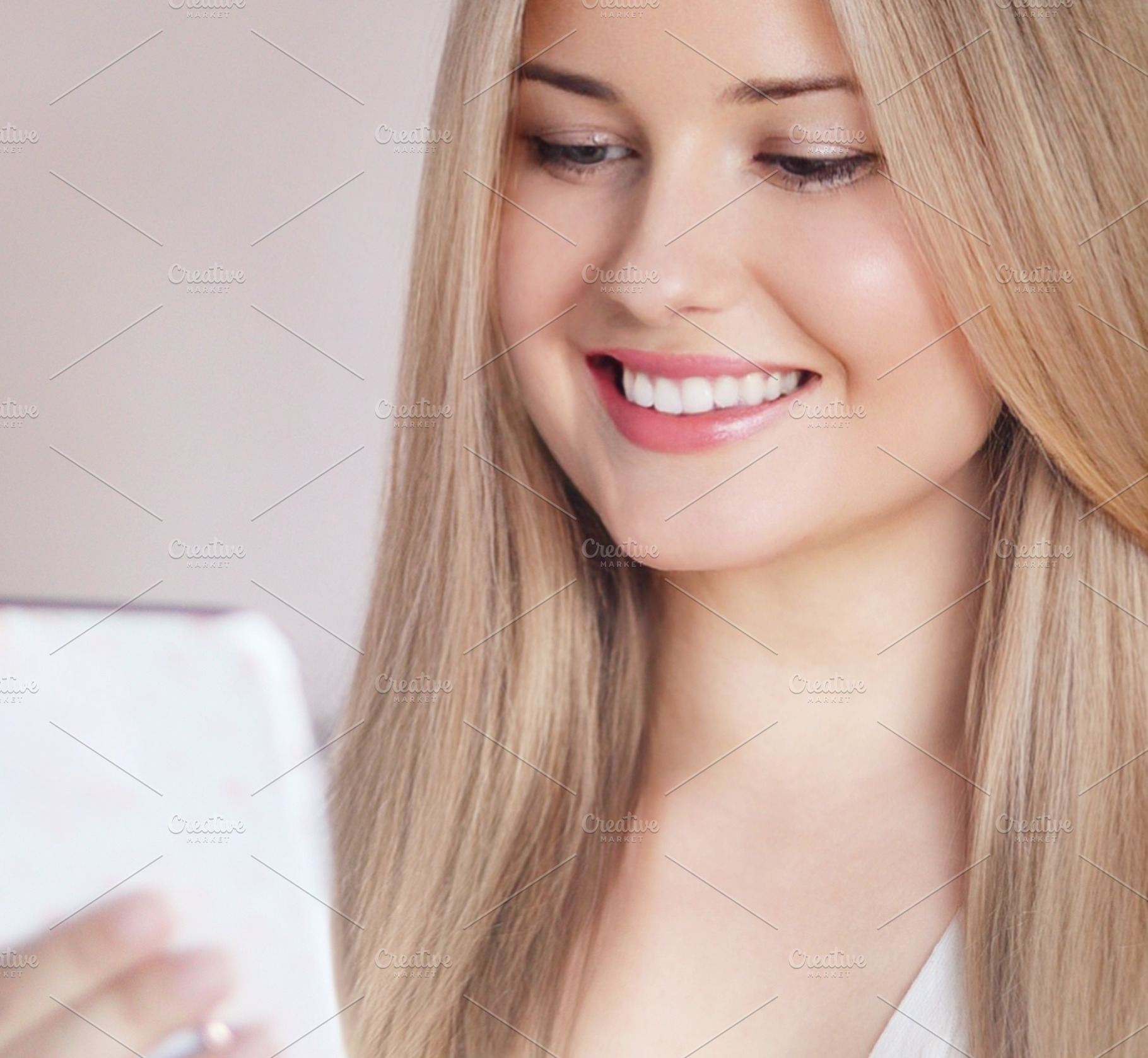 Young woman smiling while looking at a mobile phone, showing healthy teeth, nat, a Person Photo by Studio ANNA