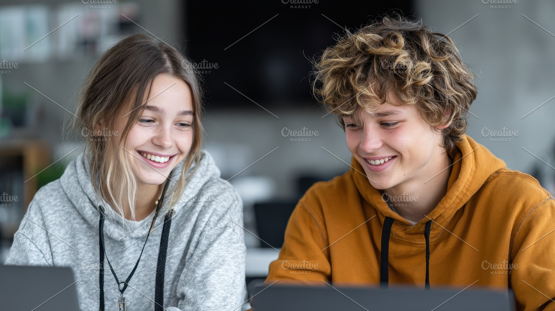 Two smiling teens using laptops toge, a Photo by Pixeness Studio