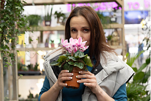 Woman in a florist smelling a flower, a Person Photo by Nenahliadava Design