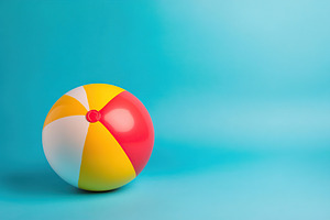Colorful beach ball resting on pastel blue background for summer fun, an Arts & Entertainment Photo by AlyaAnd