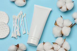 White tube, cotton pads and cotton flowers on a blue background,, a Beauty & Fashion Photo by ndanko
