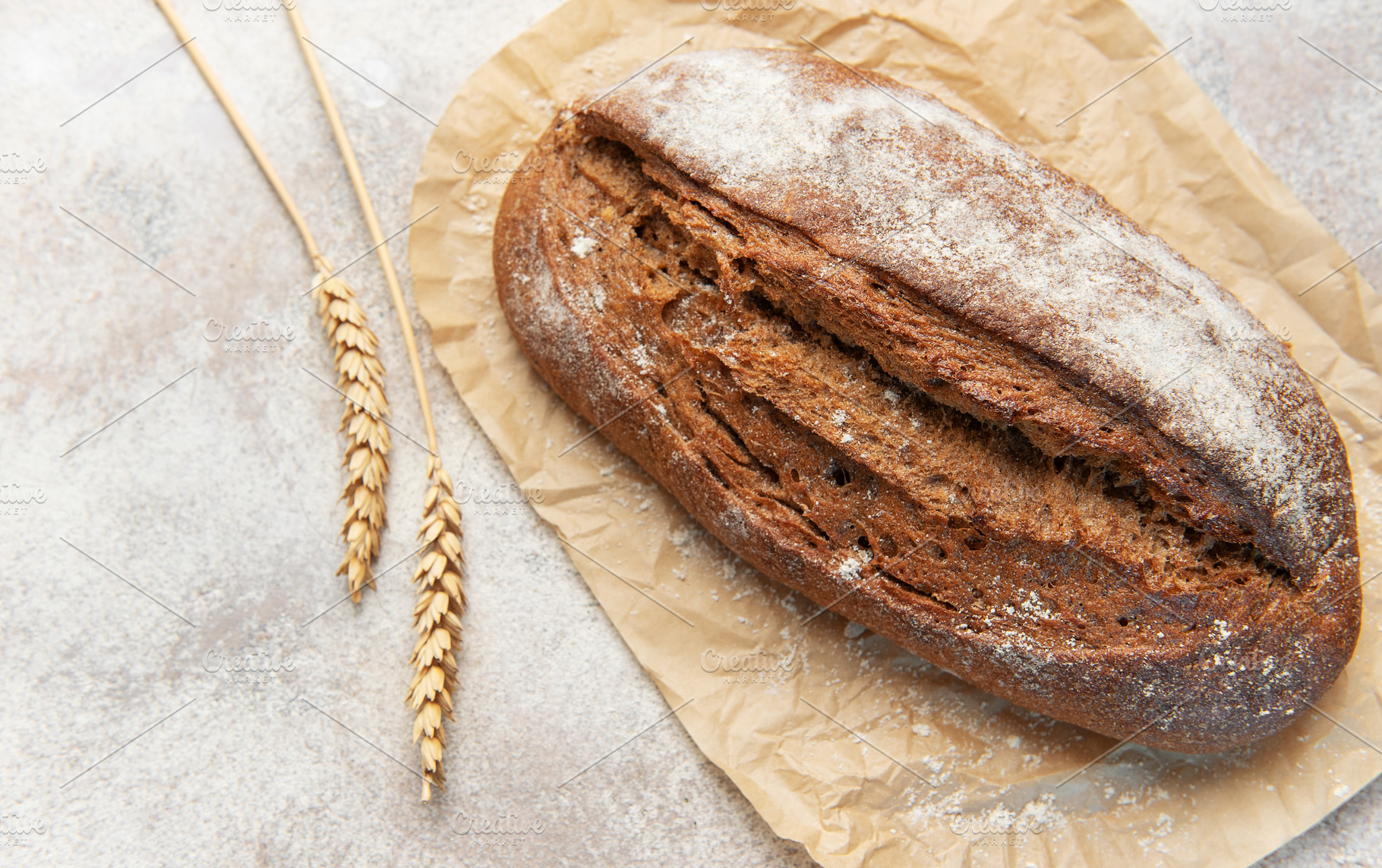 Rye bread loaf with wheat ears on parchment paper, a Food & Drink Photo by Olena Rudo