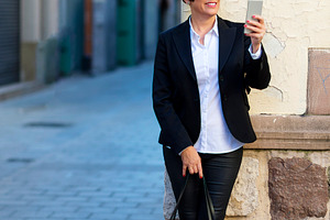 Businesswoman using smartphone in city street, a Photo by RF Images