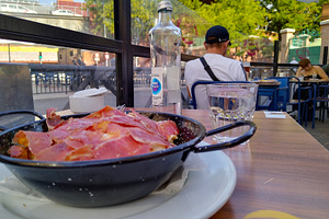 Outdoor café tapas with sliced ham and empty glass, a Food & Drink Photo by DanFLCreativo