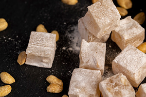 Turkish delight in powdered sugar with nuts inside, oriental sweets Turkish del, a Photo by rsoollAI