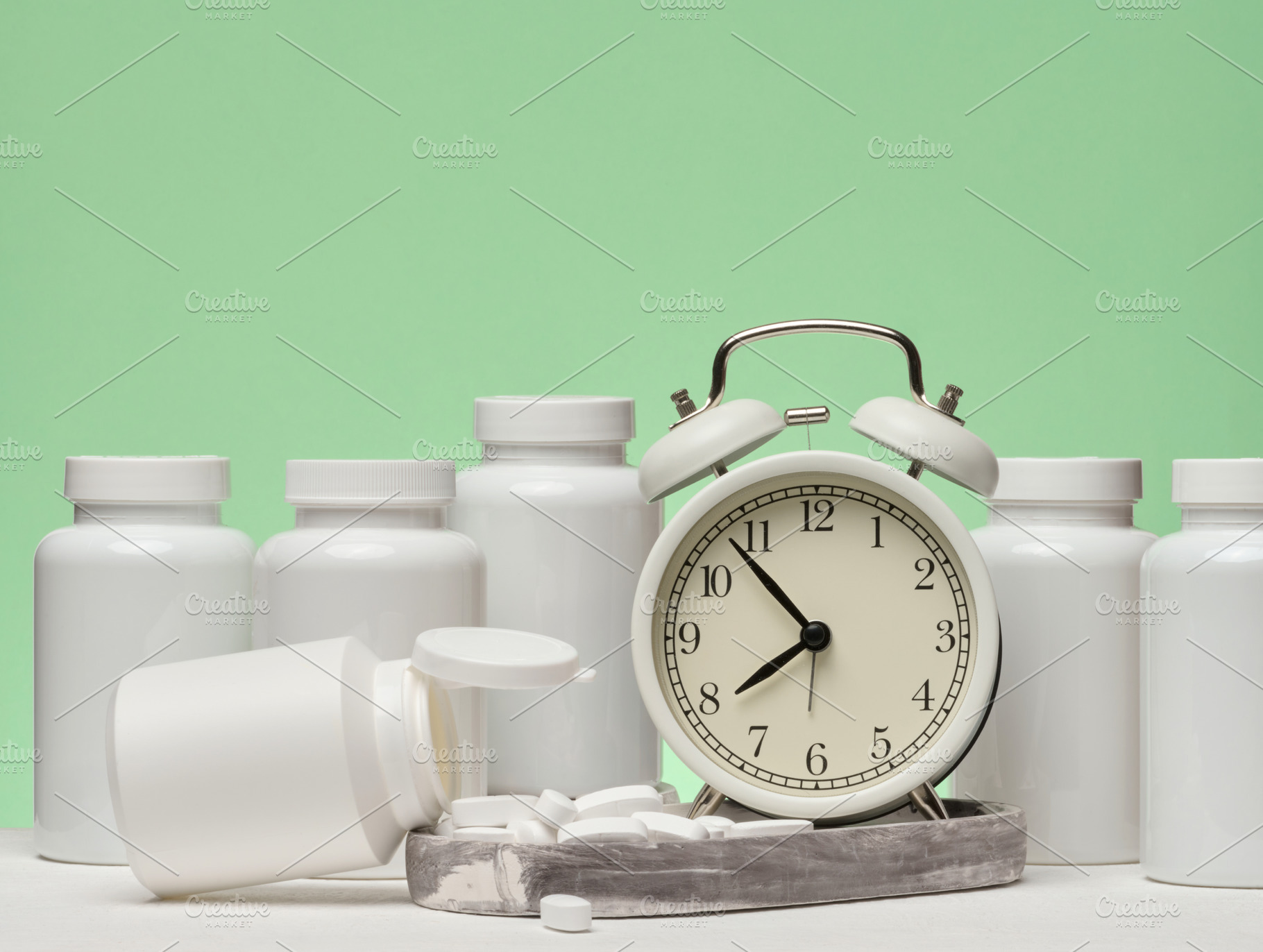 A set of white plastic pill bottles and an alarm clock are place, a Health & Medical Photo by ndanko