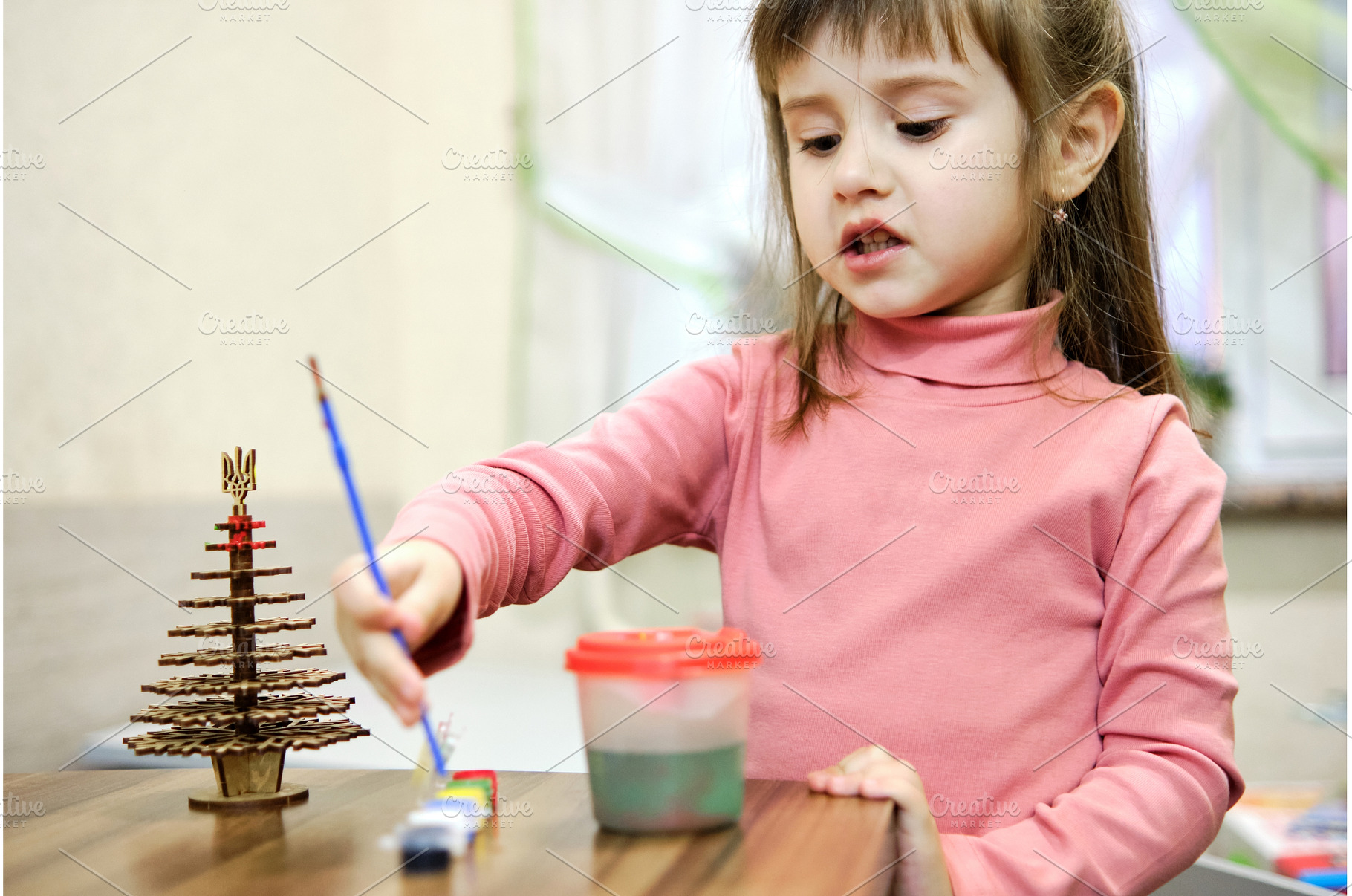 A little girl paints a wooden toy in, a Holiday Photo by Rohan Photography