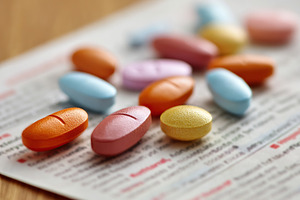 Several colorful pills scattered on a printed sheet of medication information i, a Health & Medical Photo by AlyaAnd