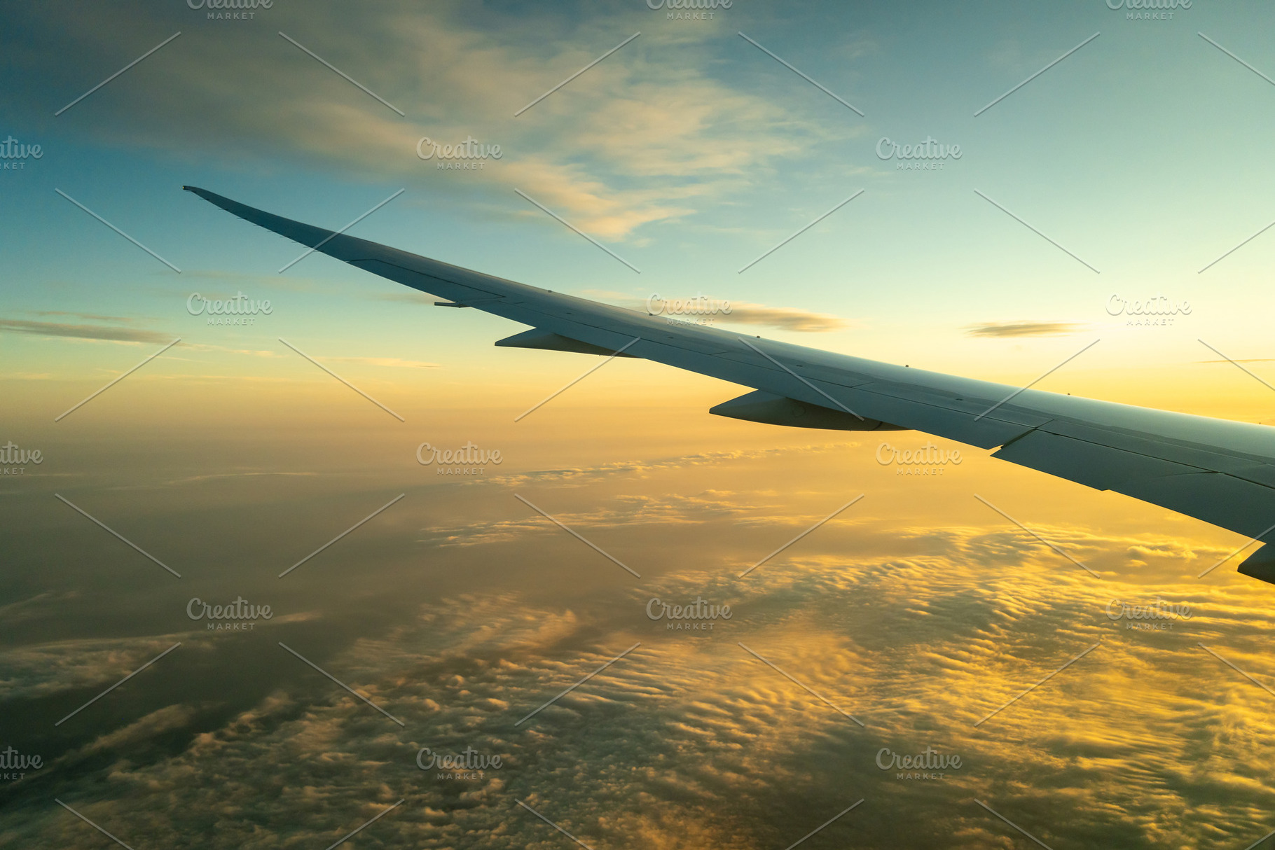 Airplane wing above the clouds during golden hour flight, a Transportation Photo by GoodGoods