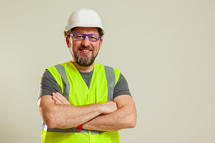 worker in a vest and white helmet, a Person Photo by Photostock