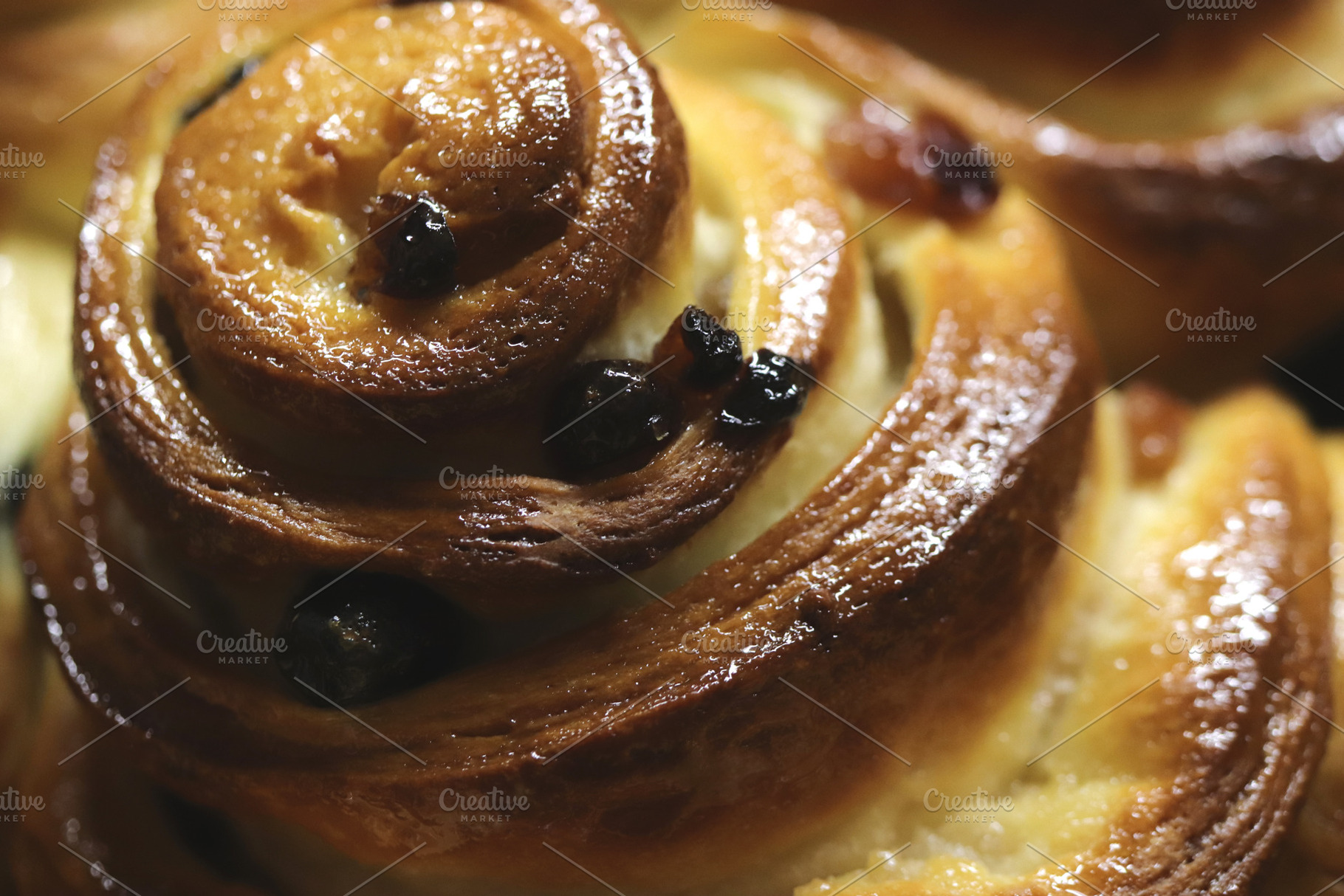 A close-up of a freshly baked cinnamon roll with raisins, showcasing its golden, a Food & Drink Photo by Textures & Backgrounds