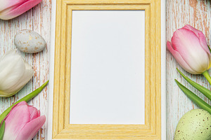 Easter eggs and tulips framing blank picture frame on wooden bac, a Holiday Photo by Olena Rudo