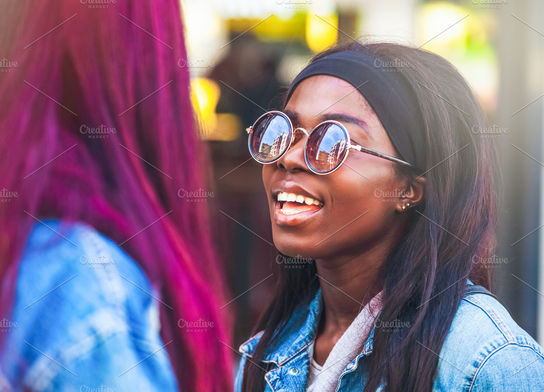 Young black woman wearing sunglasses talking with a friend with vivid hair colo, a Person Photo by Antonio Gravante Market