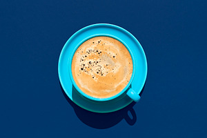 Cup of coffee above view on a blue background. Hot coffee in a b