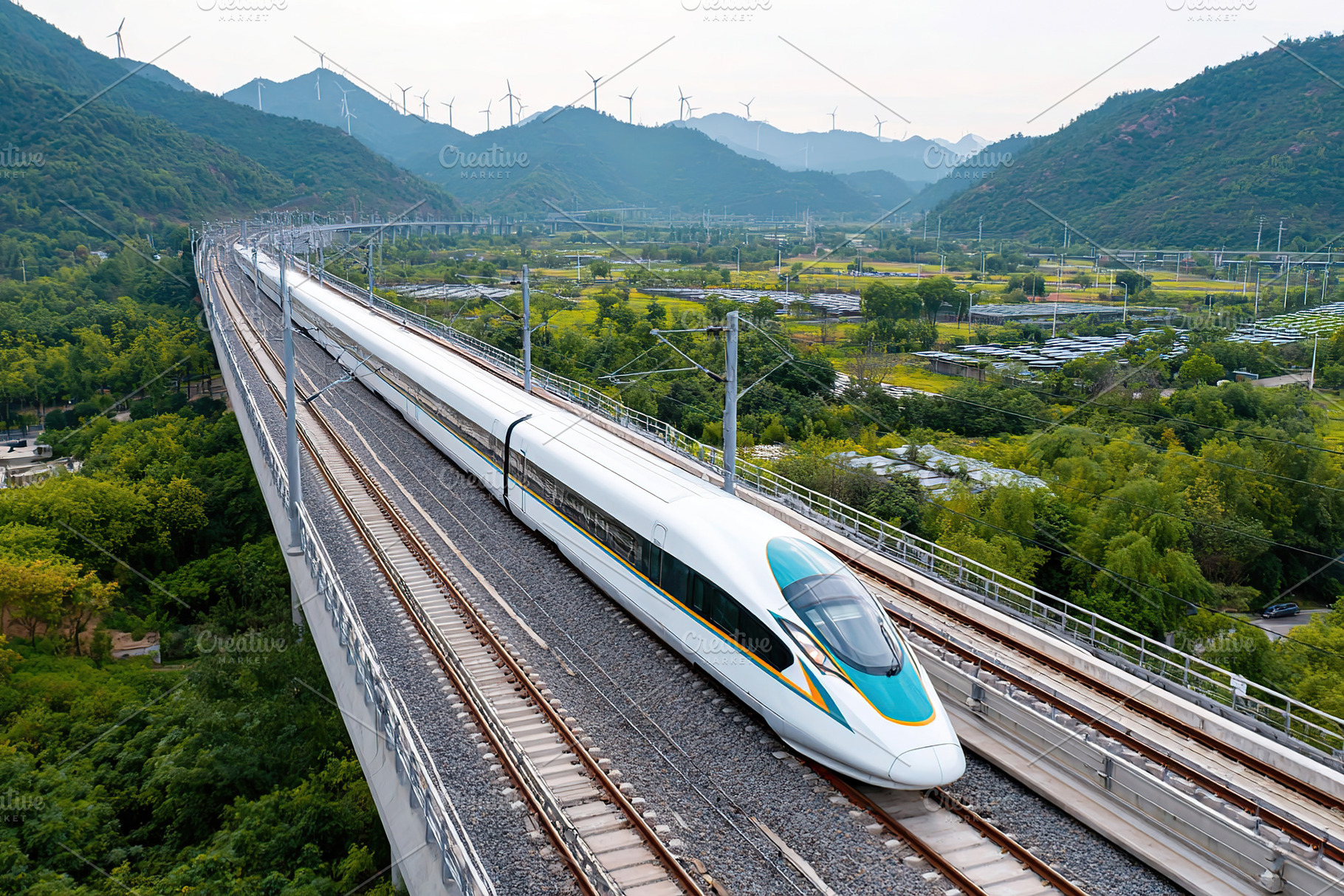 High-speed train traveling through mountainous region with wind turbines at sun, a Photo by AlyaAnd