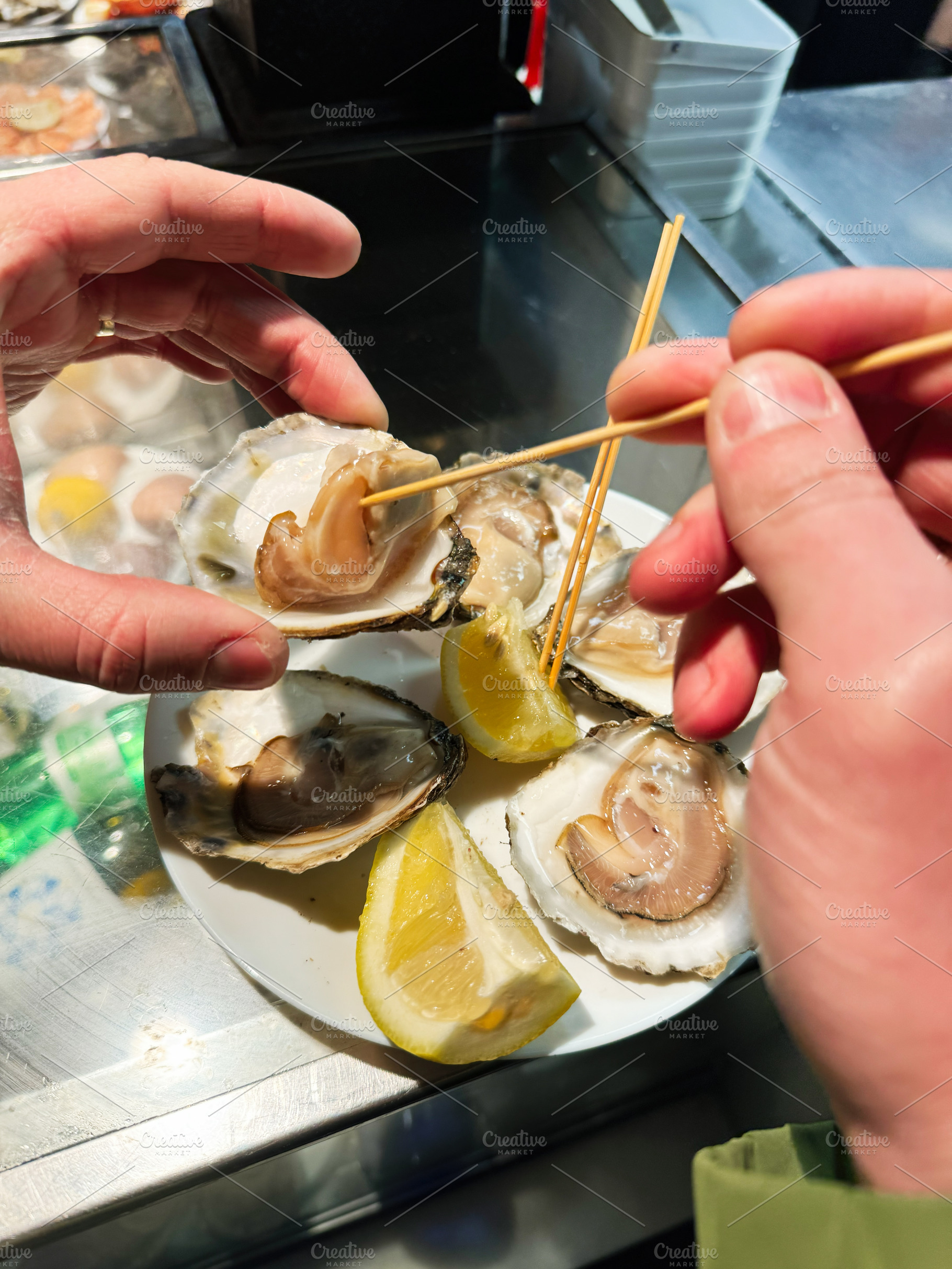 Fresh oysters served with lemon slices at a seafood market food stall, a Photo by AS photostudio