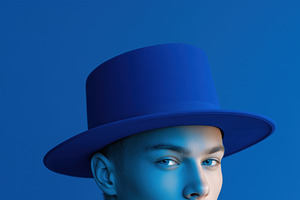 A young man with a striking blue hat mockup against a blue background, showcasi, a Hat Mockup by Textures & Backgrounds