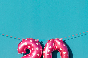 pink number 20 balloons against a vivid blue wall, a Photo by Nito