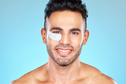 Portrait, face and eye mask with a man model in studio on a blue background for antiaging skincare. Product, wellness and beauty with a handsome young male using cosmetic treatment for dermatology, a Photo by Peopleimages.com