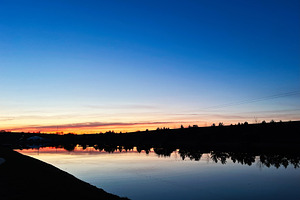 Serene sunset over a calm lake with trees and reflections, a Photo by AS photostudio