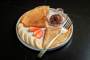 A plate of crepes filled with chocolate spread and topped with banana slices an, a Food & Drink Photo by Budarinphoto
