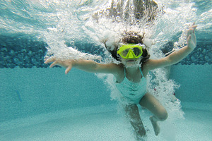 Girl swimming underwater containing bubbles, pool, and water