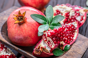 Ripe pomegranate fruits on the wooden background., a Food & Drink Photo by Volff
