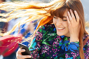 Redhead young woman laughing while looking at her smartphone and holding her ha, an Abstract Photo by Antonio Gravante Market
