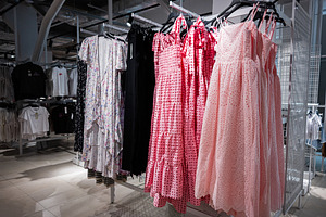 Wide selection of dresses on racks inside a retail clothing store, a Photo by AS photostudio