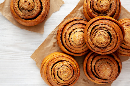Homemade Cinnamon Roll Pastry on a white wooden background, top, a Food & Drink Photo by LiudmylaChuhunova
