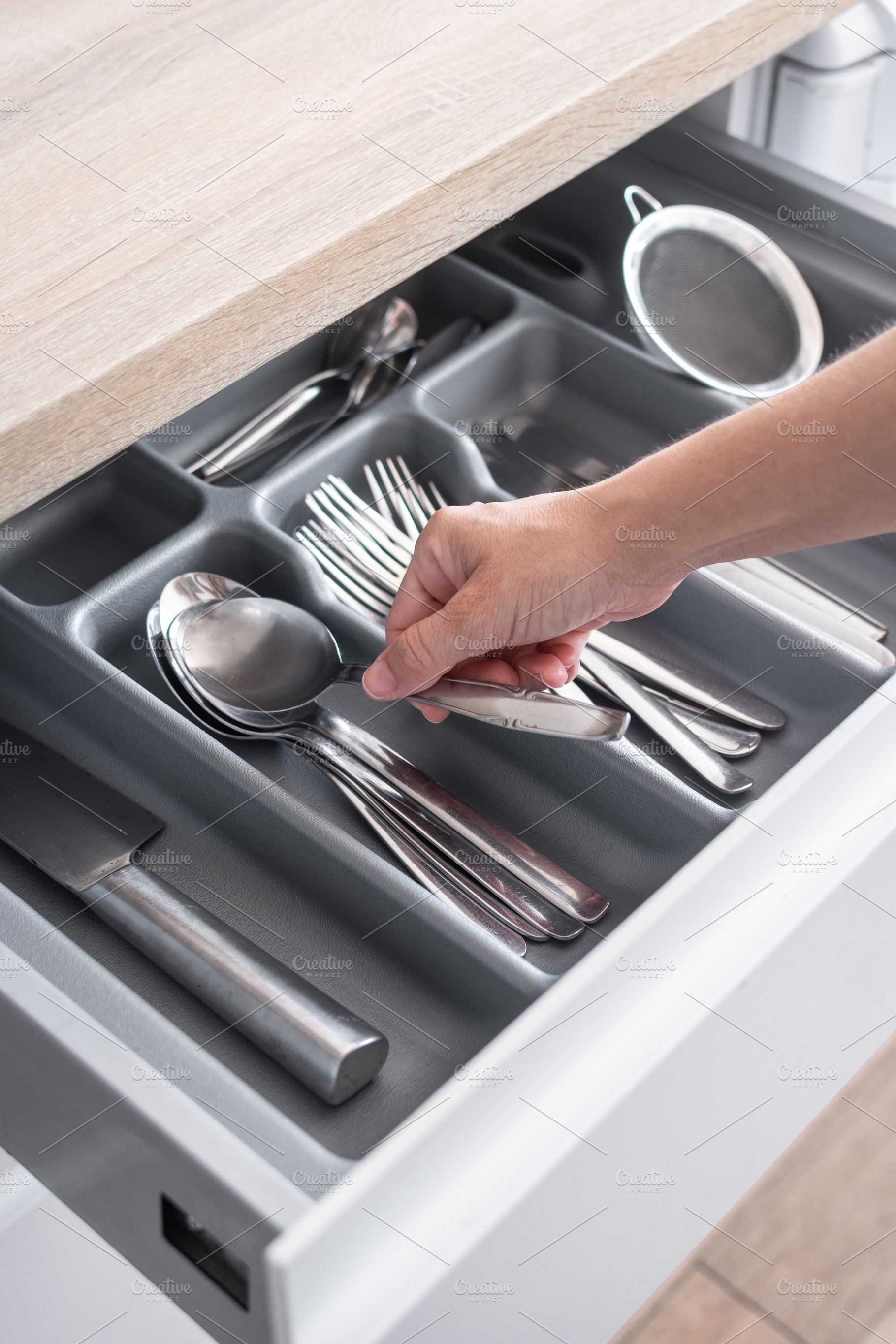 Hand picking up a spoon from an organized kitchen drawer, a Food & Drink Photo by etorres69