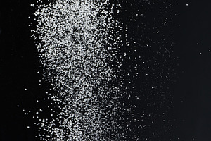 Close-up of white granular particles sugar, falling against a bl, a Food & Drink Photo by ndanko